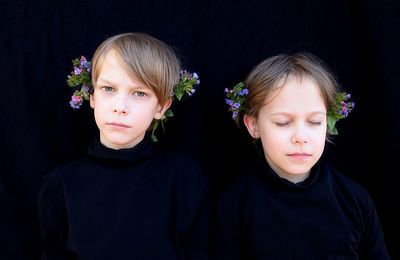 Portrait of cute girl with flowers on black background