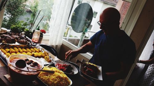 Mature man serving foods in plate