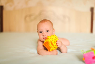 Portrait of cute baby girl lying on bed at home