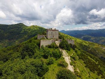 Castle on mountain against cloudy sky