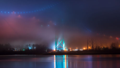 Illuminated bridge over river at night