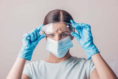 Portrait of young woman wearing mask against white background