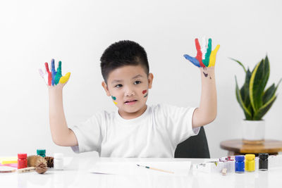 Portrait of boy holding multi colored umbrellas on table