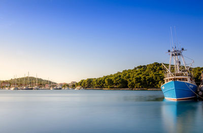 Boat moored on river against clear blue sky