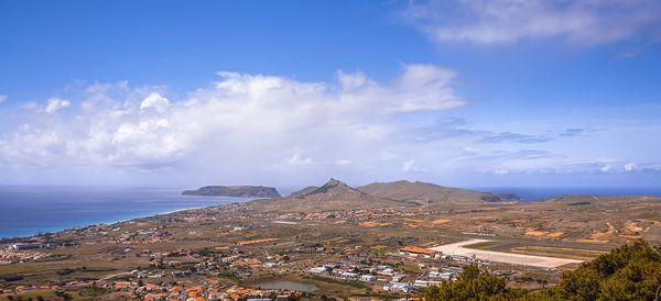 Aerial view of city by sea against sky