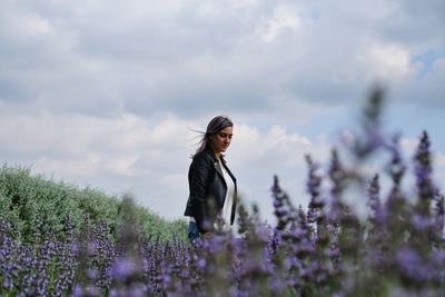 Rear view of woman standing on field against sky