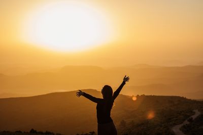 Silhouette woman standing by tree against sky during sunset