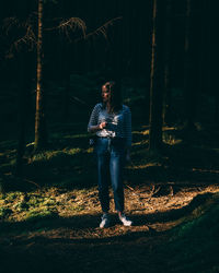 Full length of young man sitting on tree trunk