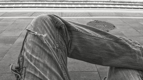 Midsection image of man sitting at railroad station platform