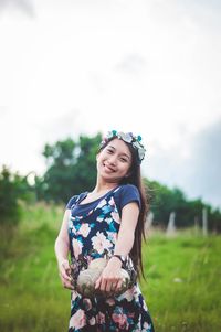 Portrait of happy woman carrying stones on grassy field