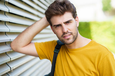Portrait of young man standing by wall outdoors