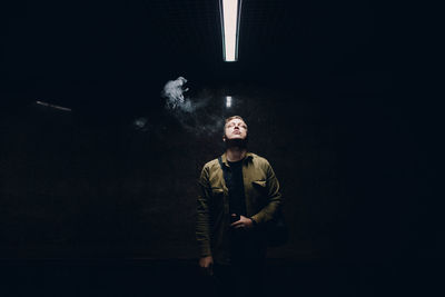 Digital composite image of man smoking cigarette against black background