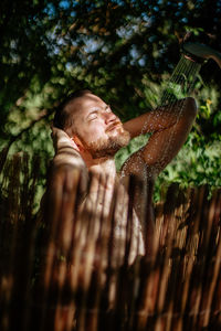 Man taking shower behind fence