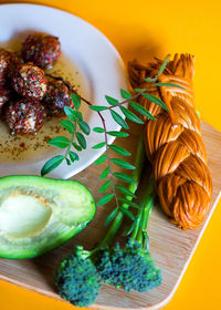 High angle view of food served on cutting board over yellow background