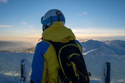 Rear view of man standing on snowcapped mountain