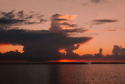 Scenic view of sea against dramatic sky during sunset