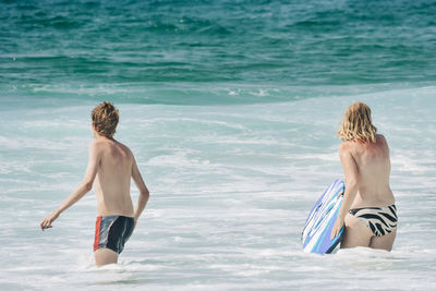 Rear view of shirtless boy on beach