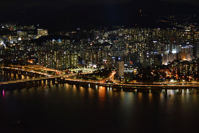 Illuminated buildings by river at night