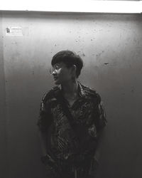 Young man looking away against wall
