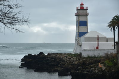 Lighthouse by sea against sky