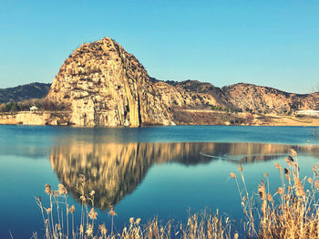 Scenic view of lake and mountains against clear blue sky