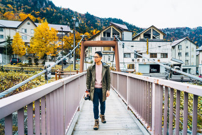 Full length of man walking on bridge against buildings