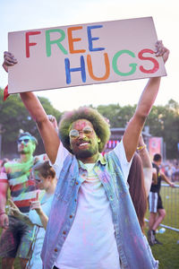 Portrait of man holding free hugs sign at carnival