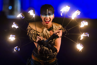 Young woman holding sparkler at night