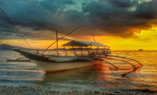 Fishing net on sea against sky during sunset