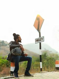 Side view of a young man with arrow sign on road