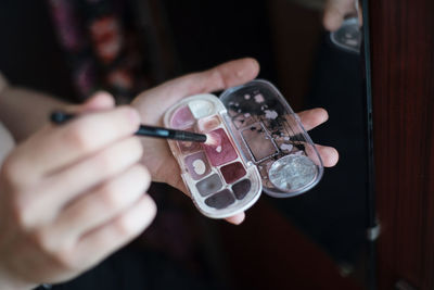 Close-up of hand holding make-up brush and beauty product