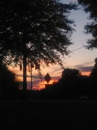 Silhouette trees on field against sky at sunset
