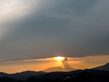 Silhouette mountains against dramatic sky during sunset