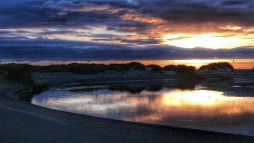 Scenic view of sea against cloudy sky at sunset