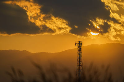 Silhouette communications tower against sky during sunset