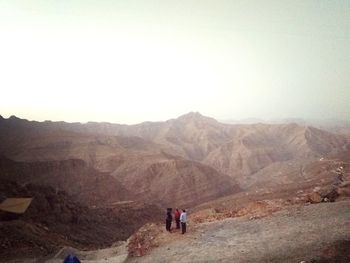 People on mountain against clear sky