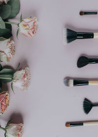Directly above shot of roses and make-up brushes on table