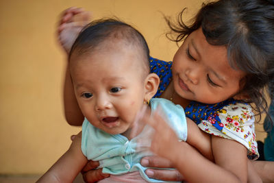 Close-up of girl holding sibling at home