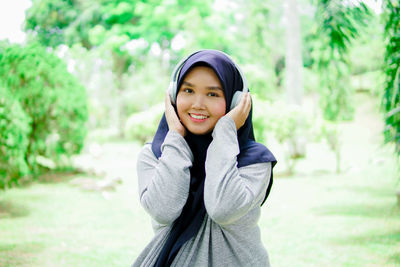 Portrait of young woman standing against trees