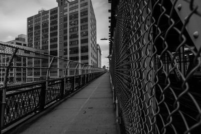 Footbridge in city against sky