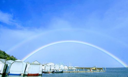 Scenic view of rainbow over sea against blue sky