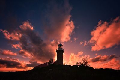 Low angle view of silhouette lighthouse against sky during sunset