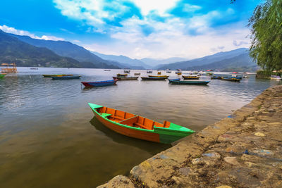 Boats moored in lake against sky