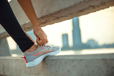 Low section of woman standing on concrete wall