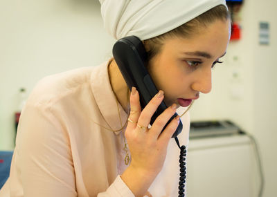 Woman wearing headscarf talking on telephone