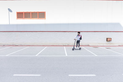 Young man riding e-scooter on parking deck