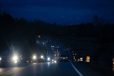 Road passing through illuminated lights at night