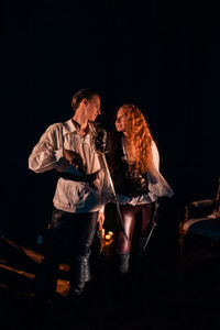 Man and woman wearing mask against black background