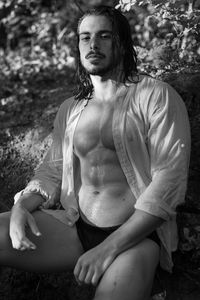 Portrait of wet man sitting on rock