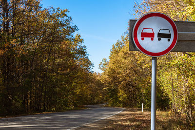 Road sign by street against sky